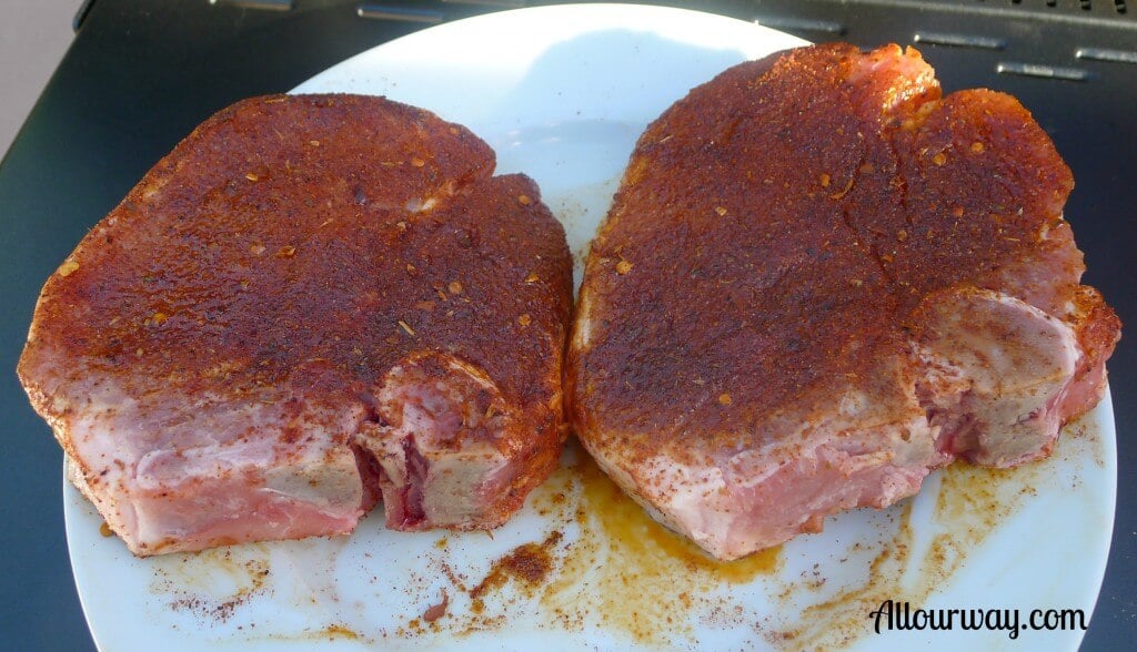 Bone-in pork chops sprinkled with meat rub.