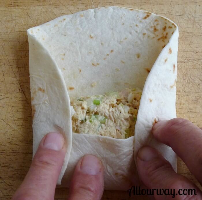 Flour tortilla with bottom covering the tuna salad and both right and left ends turned toward the center. 