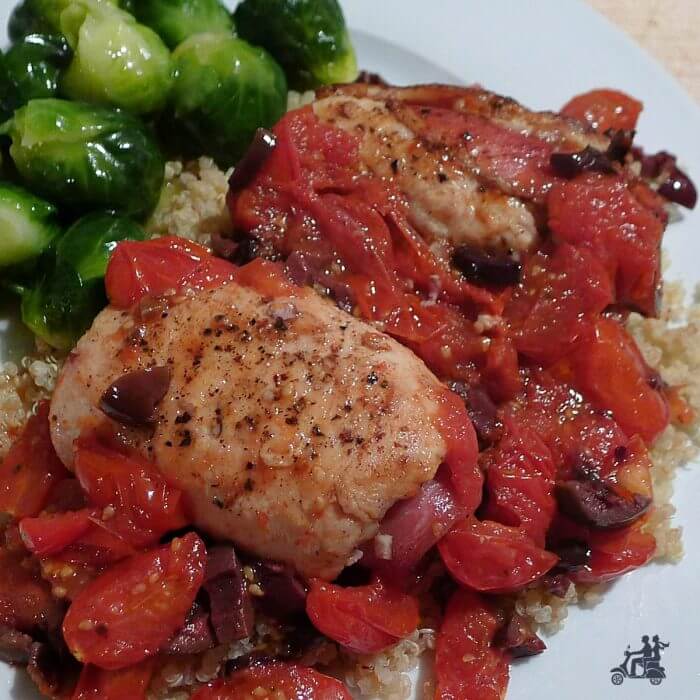  White plate with chicken saltimbocca in a fresh tomato kalamata olive sauce and Brussel Sprout. 