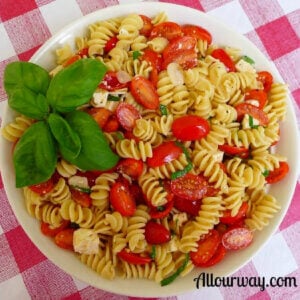A bowl of rotini pasta with grape tomatoes and a lemon vinaigrette.