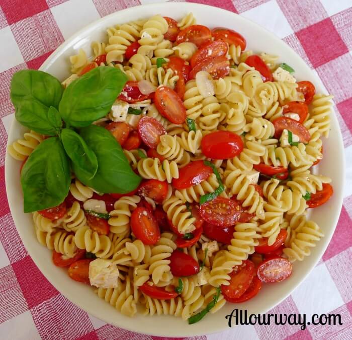 Rotini with Fresh Lemon, Grape Tomatoes and Basil in a white bowl on top of a red and white checkered tablecloth. 