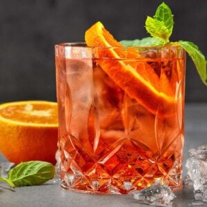 Aperol Spritz made with a slice of orange and a sprig of mint in the glass.