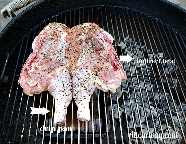 Butterflied chicken on the grill ready to cook with the bird over a drip pan and the coals off to the side. 