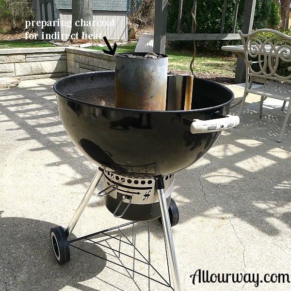 A kettle grill outdoors with a charcoal chimney full of charcoal ready to be lit.