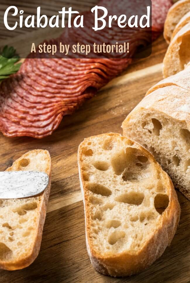 slices of ciabatta bread on wooden breadboard with salami slices and a knife.