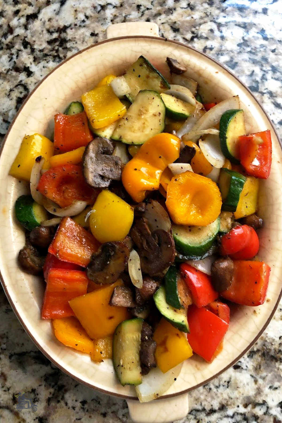 A bowl filled with grilled peppers, mushrooms, and onion. 