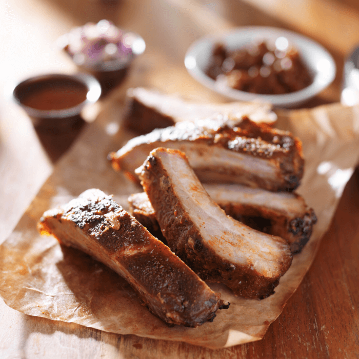 Smoked Pork Ribs on Brown Parchment paper with condiments in background