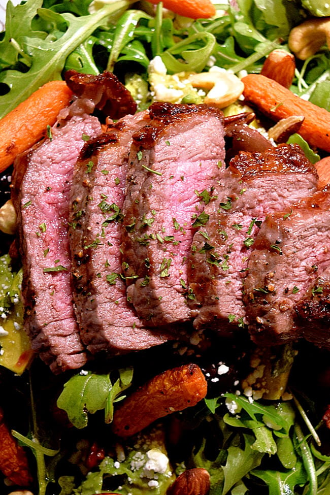 Sliced London broil on top of an arugula salad with grilled carrots. 