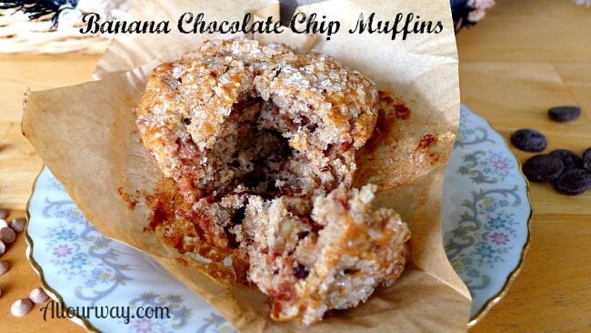 Sliced Banana Chocolate Chip Muffin on brown parchment paper on top of a white saucer with blue and red flowers around the rim- Just a Bite @Allourway.com