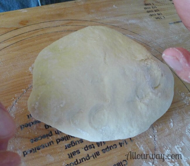 Grissini - Italian breadsticks dough resting on a wooden bread board. 