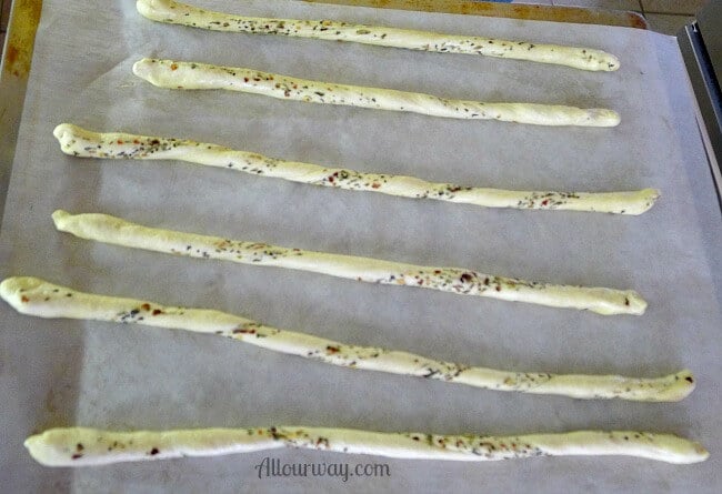 Grissini breadsticks formed on parchment covered baking sheet ready to bake.