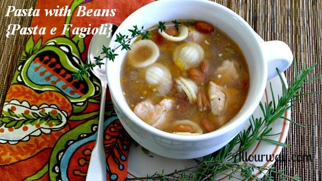 Pasta with Beans {Pasta e Fagioli} with thyme and rosemary in a large white soup mug with a soup spoon on top of a rust, turquoise, green napkin all on top of bamboo placemat. @ Allourway.com