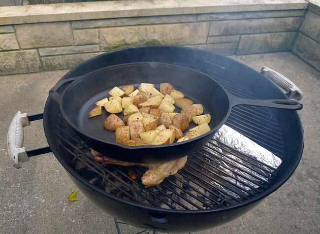 Cast iron skillet with potatoes is placed on top of the chicken to flatten it @allourway.com