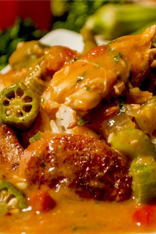 A plate piled high with Louisiana Chicken Gumbo featuring okra slices, chunks of chicken, onions and tomatoes over white rice. 