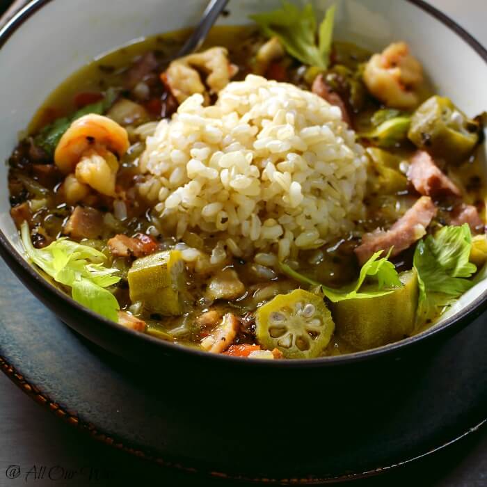 Closeup of Louisiana Shrimp Gumbo in brown bowl with a scoop of rice. 