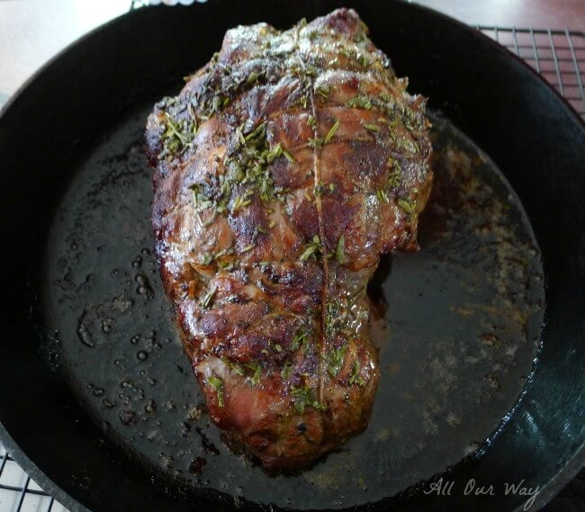 Boneless leg of lamb nice and brown in a black cast iron skillet. 