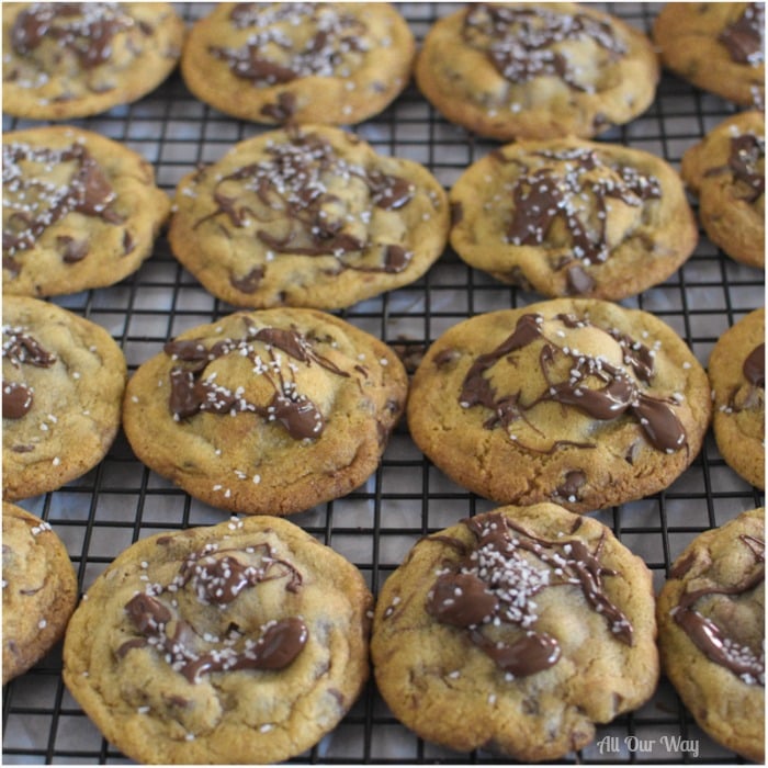 Salty Sweet Nutella Chocolate Chip Cookies are lined up in rows on a black cooling rack.