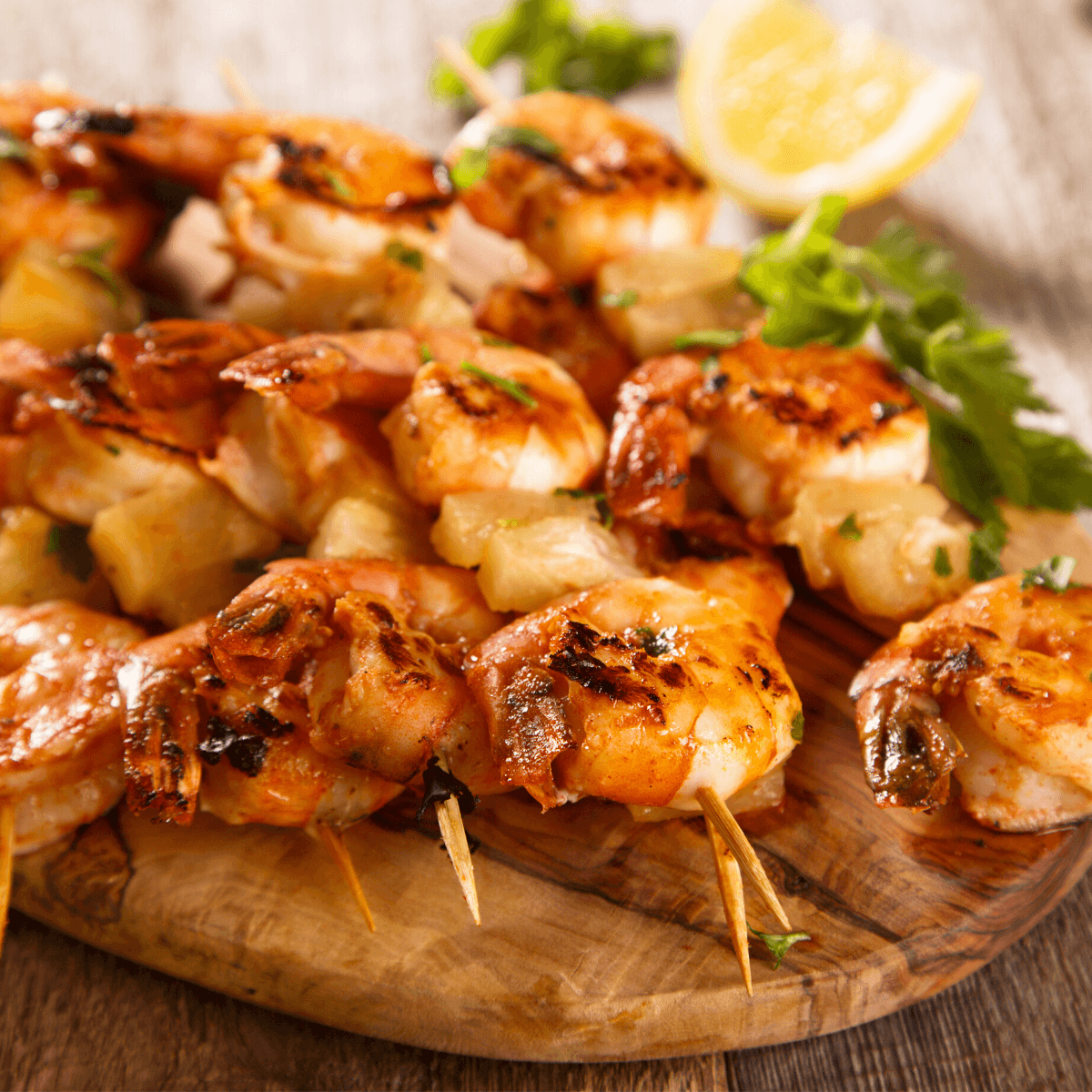 Skewered grilled shrimp with parsley and lemon on wooden board. 