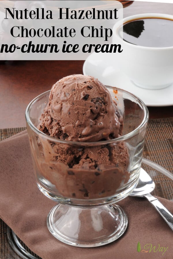 Two scoops of chocolate ice cream in glass goblet with white cup of coffee in background and silver spoon next to glass goblet. 