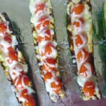Zucchini boats grilled and stuffed with mozzarella cheese and topped with grape tomato halves.
