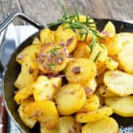 Browned sliced potatoes fried in black skillet with onions and herbs.