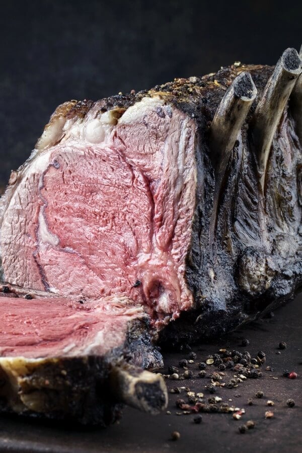 Close up of a dry aged standing rib roast cook medium rare with one slice cut off. 
