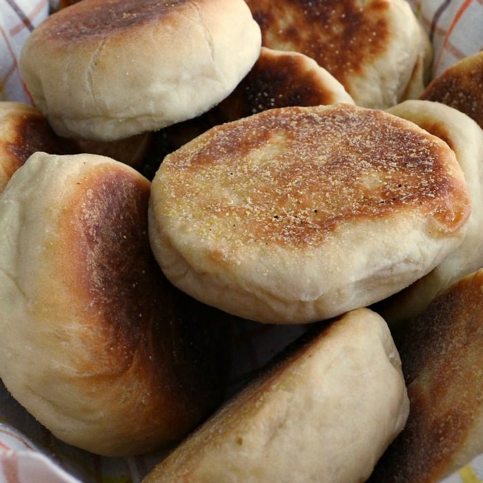 Close up of browned English Muffins in a towel lined basket. 