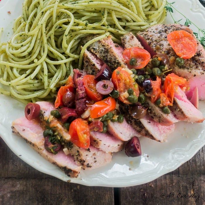 Southern Italian Grilled Tuna Steaks with a fresh grape tomato and black olive sauce to top the delicious sliced medium rare tuna along with green pesto pasta.