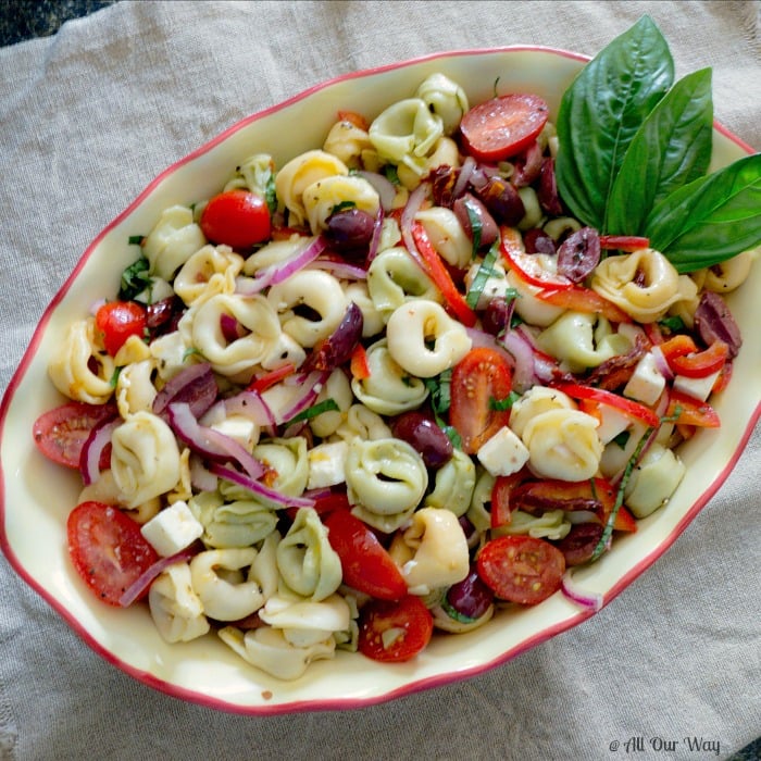 Red, Green, White colored Cheese Tortellini Salad With Sun-Dried Tomatoes a deep yellow and red bowl