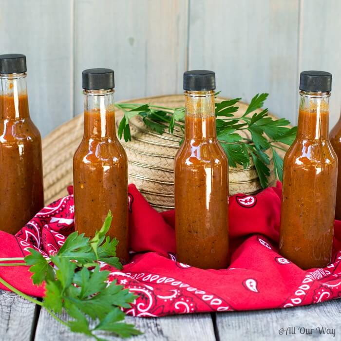 Four bottles of hot sauce on a red bandana handkerchief. 