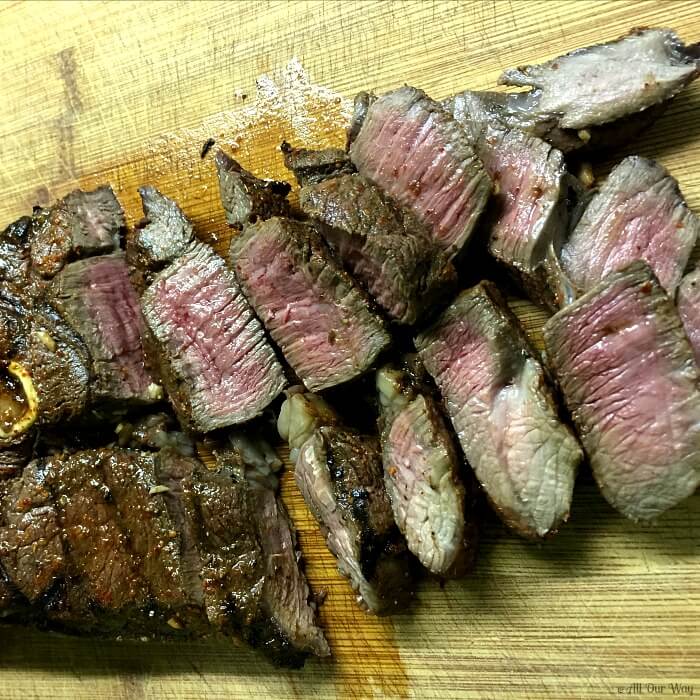 Venison steak cooked to medium rare and sliced on a cutting board. 