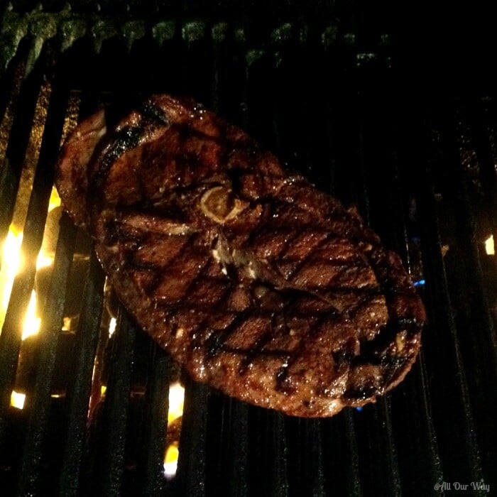 Venison steak over a hot fire on a black grill. 