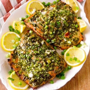 Italian Pesto Salmon recipe on a white plate with lemon slices.