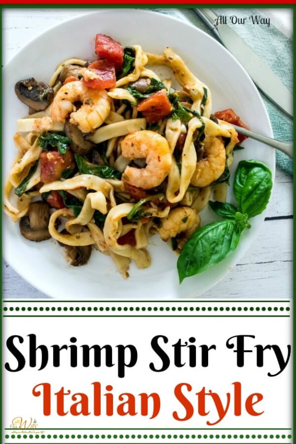 Shrimp stir fry over fettuccini on white dish with basil, tomatoes, and spinach. 