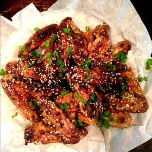 Spicy Teriyaki Chicken Wings Are Finger Licking Good are rich with glaze and on a white piece of parchments paper.