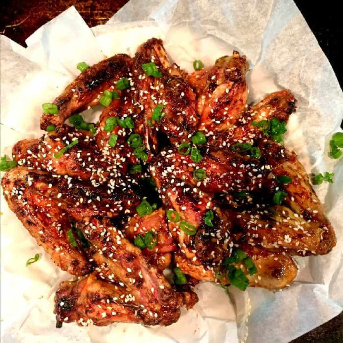 Spicy Teriyaki Chicken Wings Are Finger Licking Good are rich with glaze and on a white piece of parchments paper.