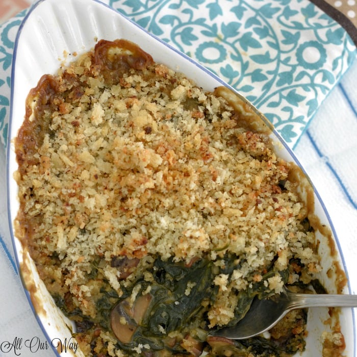 White gratin dish with spinach gratin. White and blue tea towel on side.