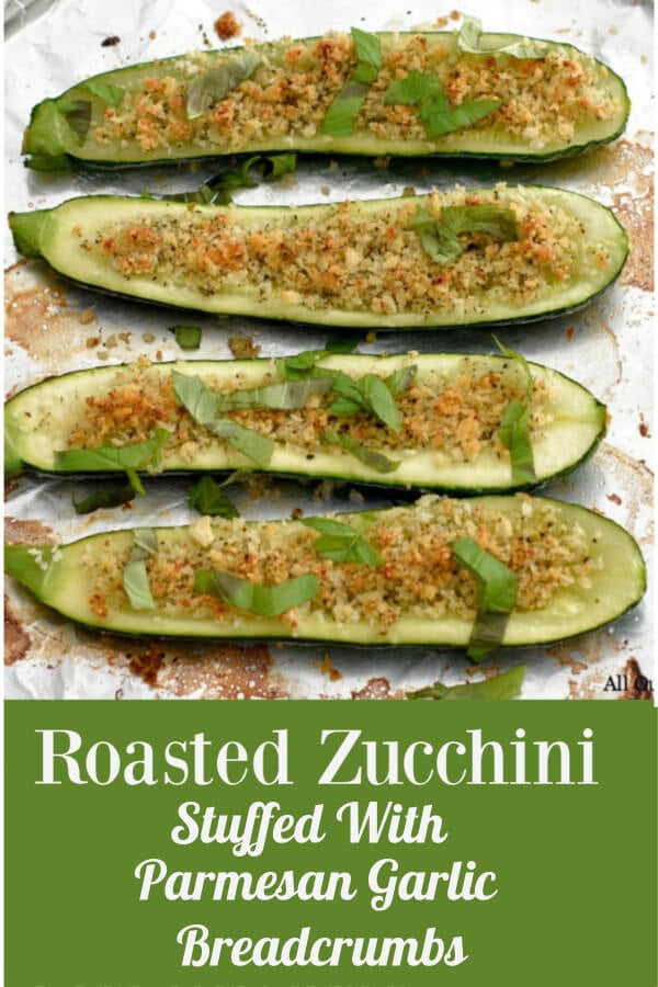Zucchini boats stuffed with breadcrumbs and sprinkled with basil ribbons on an aluminum covered round baking sheet. 