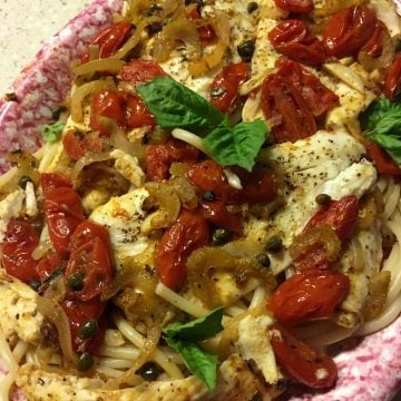 Flounder fillets on a red and white plate with grape tomatoes