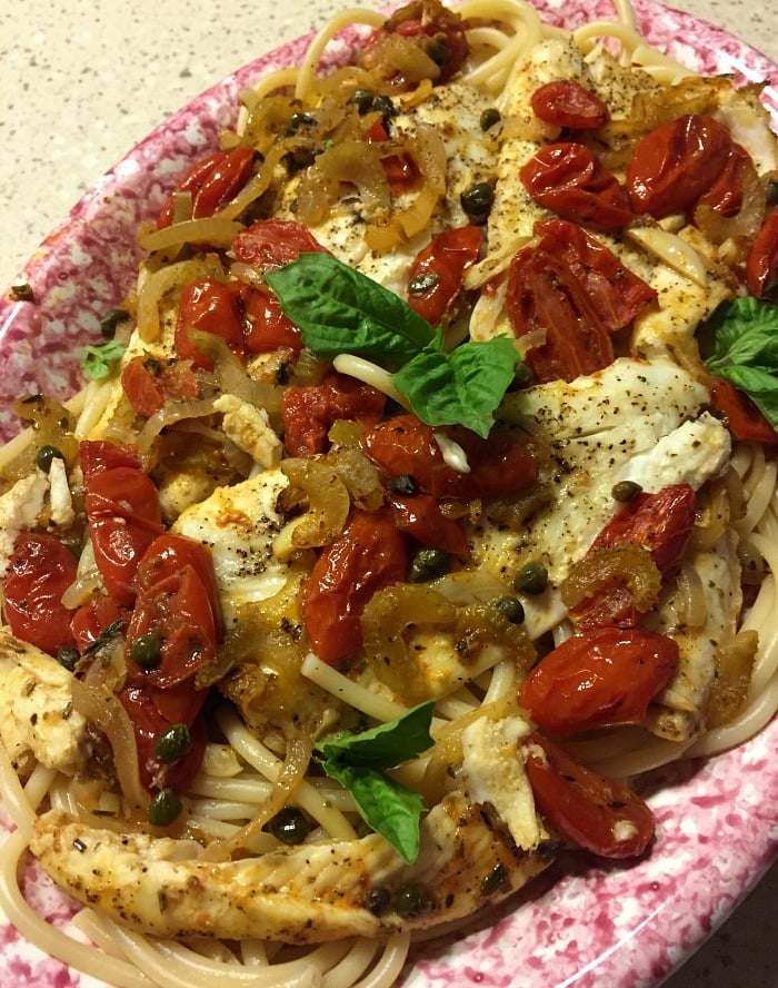 Flounder fillets on a red and white plate with grape tomatoes
