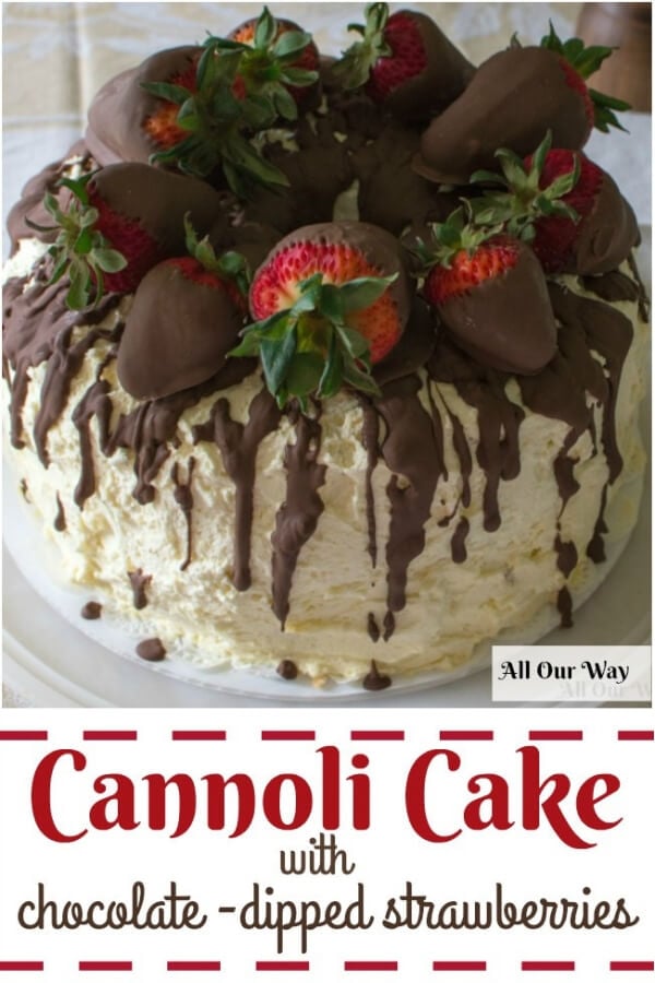 Whipped cream frosted cannoli cake with a chocolate glaze on top and chocolate strawberries. 