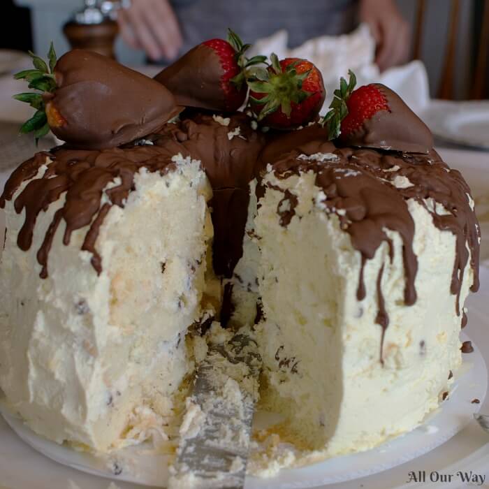 Cannoli cake filled with sweetened ricotta cheese and chocolate chips, frosted with whipped cream and chocolate-dipped strawberries.