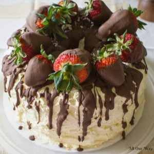 Cannoli Cake filled with sweetened ricotta cheese and chocolate chips and topped with whipped cream and chocolate-dipped strawberries.