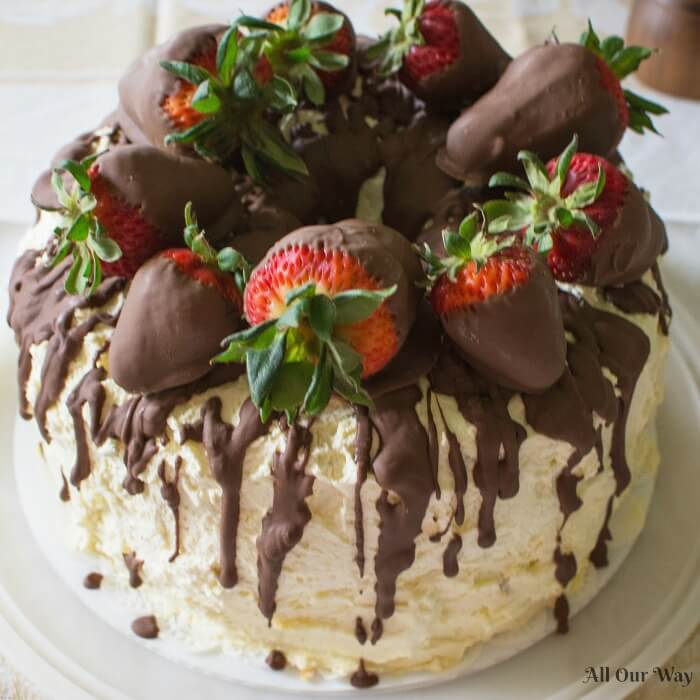 Cannoli Cake filled with sweetened ricotta cheese and chocolate chips and topped with whipped cream and chocolate-dipped strawberries. 