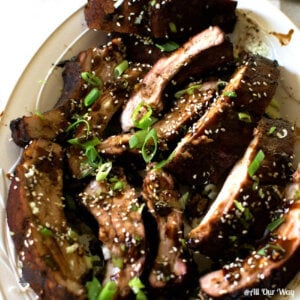 Asian barbecued ribs are sticky, sweet, salty, spicy .on a plate sprinkled with green onions.