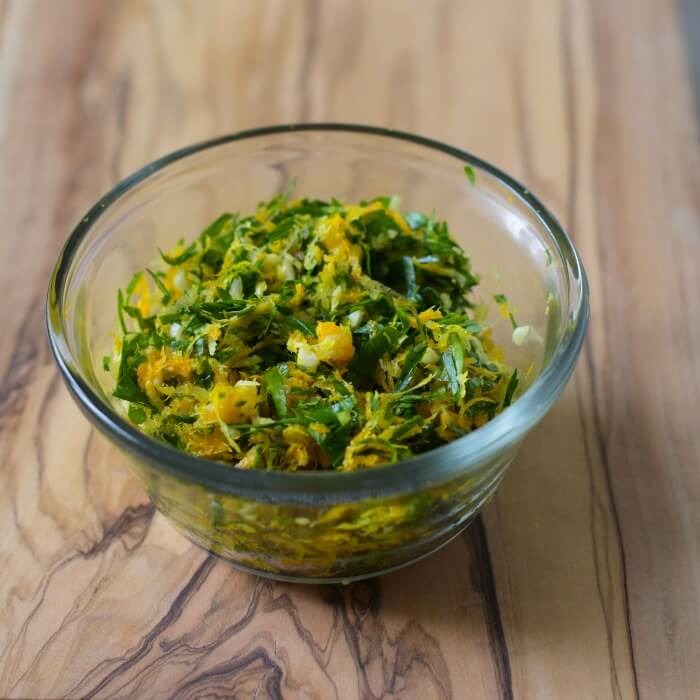 Bowl of gremolata - a mixture of grated lemon, orange zest with garlic and fresh Italian parsley. 