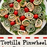 A large white platter filled with colorful spinach and red pepper tortillas and green arugula and grape tomatoes in between the round pinwheels.