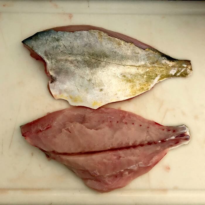 Two Florida Pompano fillets on white cutting board. 