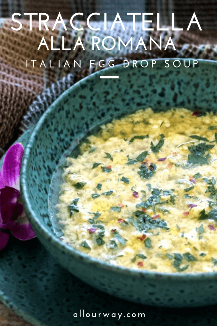 Egg soup in turquoise speckled pottery bowl with brown-blue plaid towel and purple blossom on side of bowl. 