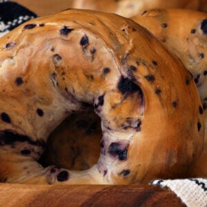 Close up of a fruit nut brown bagel in a white linen lined wooden basket.